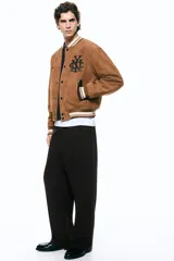 Pantalón relaxed fit color marrón, confeccionado en tejido suave, con cintura elástica ajustable mediante cordón, bolsillos laterales discretos, bolsillo posterior insertado y piernas rectas con pliegues frontales y traseros.