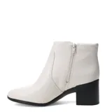 Botas de caña baja marca Bottero, confeccionadas en cuero color marfil, con taco cuadrado negro y punta redondeada.