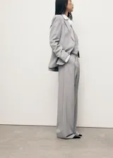 Pantalón de sastreria gris con diseño de raya diplomática, de tiro bajo, corte recto y amplio con pinzas delanteras y trabillas para cinturón.