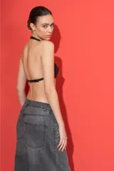 Mini top de cuero sintético negro con diseño tipo halter, con cierre frontal mediante hebilla metálica y tirantes ajustables.