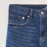 Pantalón de jean de calce slim, color azul medio, con cinco bolsillos y tiro medio.