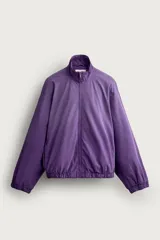 Cazadora relaxed fit de denim de algodón en color violeta, con efecto lavado, cuello alto, cierre frontal de cremallera y bolsillos en las costuras laterales. Presenta puños y dobladillo elásticos.