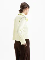 Camisa de jacquard con diseño de flores sutiles, color blanco, con cuello amplio de puntas marcadas, mangas largas con puños y cierre frontal con botones.