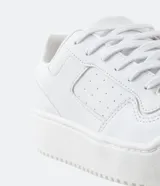 Championes blancos de caña baja con cordones, recortes laterales, puntera redonda y suela texturizada de 4cm de altura.