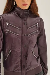 Campera estilo biker color ciruela, con múltiples cierres metálicos decorativos en el frente y mangas. Tiene cuello alto con broches, puños y cintura elastizados.