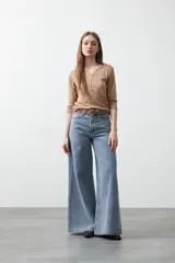 Remera de manga larga color beige, confeccionada en algodón, con escote en V y cartera corta de botones blancos.