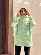 Canguro oversize de rústico de algodón con diseño a rayas horizontales en color verde menta y blanco. Presenta capucha, escote con broches frontales, bolsillo tipo canguro al frente y puños elásticos en mangas y ruedo.