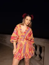 Conjunto de dos piezas compuesto por un top corto de mangas abullonadas con elástico y una falda corta con volados, ambos confeccionados en tela estampada a rayas multicolores.