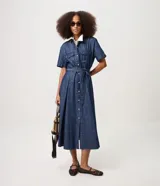 Vestido midi de jean azul, de manga corta, con bolsillos frontales con solapa, cierre frontal de botones y cinturón ajustable para anudar en la cintura.