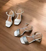 Sandalias de tacón cuadrado medio, con diseño de tiras finas y cierre de pulsera ajustable al tobillo. Confeccionadas en cuero sintético, presentan una punta cuadrada y un estilo minimalista y versátil.
