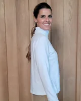 Polera de manga larga color blanco, confeccionada en algodón, con cuello alto tipo tortuga y detalles de volados en el cuello y en los puños.