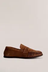 Mocasín de cuero marrón con textura croco y acabado brillante, de diseño clásico con detalle de antifaz en el empeine y costuras pespunteadas alrededor de la puntera.