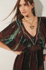 Vestido corto con escote en V y mangas cortas amplias, con elástico fruncido en la cintura. Presenta un teñido tie-dye en tonos marrón oscuro y verde azulado, con un borde de bordado de hilos de lurex plateado en el escote.