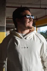 Hoodie canguro blanco de diseño oversize, con capucha, bolsillo frontal tipo koozban y sutil bordado monocromático en el pecho.