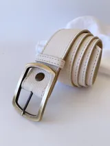 Cinto de cuero color crudo con hebilla rectangular de metal color bronce envejecido.