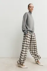Pantalón bombacho de tiro alto con estampado de cuadros en tonos crudo y marrón. Presenta cintura elástica ajustable con cordón y bajos elásticos.