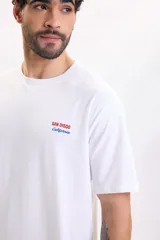 Remera blanca de manga corta con gran estampado gráfico en la espalda con la leyenda "San Diego California" y un dibujo de reposeras de playa.