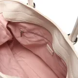 Cartera grande tipo shopper color beige, de diseño estructurado en símil cuero con detalles fruncidos en la parte superior y cordones laterales. Cuenta con doble asa de mano, correa ajustable y removible para el hombro, y aplique metálico con el logo de la marca en el frente.