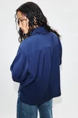 Camisa de cuello solapa y manga corta con dobladillo, presenta bolsillos de plastrón en el frente, bajo asimétrico y cierre frontal con botones ocultos.