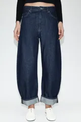 Jeans de tiro medio con diseño de pierna tipo balloon y corte full length. Presenta cintura con trabillas, cinco bolsillos clásicos, cierre frontal con cremallera y botón, y bajo acabado con vuelta.