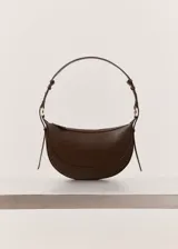 Bolso de hombro de diseño ovalado y tamaño mediano, confeccionado en material sintético con textura granulada. Cuenta con asa ajustable, cierre superior de cremallera y forro interior.