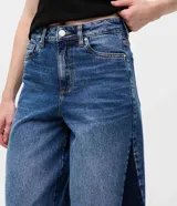 Pantalón wide leg de jean azul, de tiro medio y corte amplio, con detalle de recorte lateral en tono más oscuro y trabillas para cinturón.