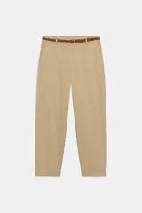 Pantalón chino color beige de tiro medio con bolsillos frontales y falsos bolsillos de vivo en la espalda. El bajo tiene un acabado con vuelta. Incluye un cinturón trenzado marrón.