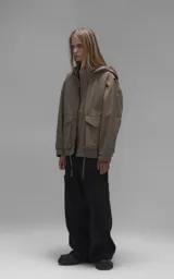Campera técnica liviana color beige, confeccionada en microfibra de alta densidad con acabado mate. Presenta mangas desmontables que permiten convertirla en chaleco, cuello tipo camisa, cierre frontal oculto bajo cartera y logo bordado en el pecho. Incluye cuatro bolsillos frontales de gran tamaño con solapa y puños con elástico.