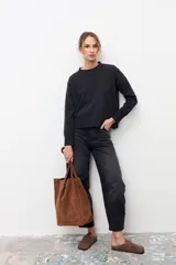 Bolso tipo tote de gran tamaño, confeccionado en gamuza color tostado. Presenta un diseño minimalista con doble asa larga para llevar al hombro y un cierre mediante cordón ajustable en la parte superior.