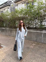 Conjunto de dos piezas de lanilla en color gris melange, compuesto por un buzo oversize de manga larga con aberturas laterales y un pantalón largo de corte recto y holgado.