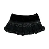 Pollera mini tipo skort de color negro, con diseño de volados de encaje y satén. Cuenta con short integrado y ajuste regular.