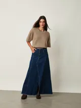 Pollera larga de denim azul con diseño de paneles, bolsillos delanteros y tajo frontal. Presenta terminación deshilachada en el ruedo.