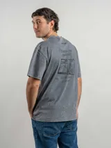 Remera oversize de algodón color negro con efecto lavado. Presenta un estampado gráfico en la espalda con la frase 'Freeze the moment' y un diseño de cámara fotográfica en tonos rojizos.