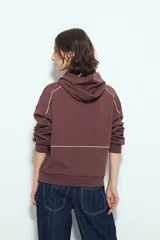 Canguro negro de silueta amplia con capucha integrada y detalles de líneas blancas que recorren el frente y las mangas.