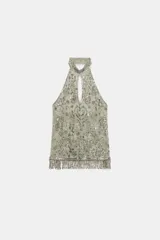 Top halter confeccionado en mezcla de poliamida, color verde militar, con diseño cut-out en el escote, espalda descubierta y aplicaciones de abalorios y lentejuelas brillantes. Presenta bajo recto con flecos colgantes de cuentas y cierre posterior con botones en el cuello.