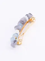 Broche para el pelo con piedras irregulares de color lila, celeste y blanco, unidas por aros dorados.