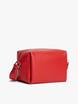 Bandolera Tommy Jeans de color rojo, diseño estructurado de silueta cuadrada con acabado liso. Cuenta con cierre de cremallera, correa ajustable y un colgante lateral de cordón trenzado con adorno en forma de corazón. Incluye la insignia con el logo de la marca en la parte delantera.