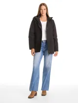 Campera 3 en 1 de color beige, con sistema de capas desmontables. La capa exterior es de tejido técnico resistente al viento y lluvia ligera, con capucha fija, cierre frontal con solapa, bolsillos de parche y ajuste elástico interno en la cintura. Incluye una campera interior capitoneada ultraliviana que puede usarse de forma independiente.