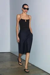 Top de poliamida color negro con escote recto, abertura frontal tipo gota y tirantes finos ajustables.