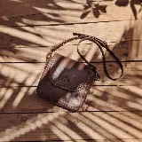 Mini cartera bandolera de cuero, de formato compacto y diseño atemporal con solapa frontal y costuras artesanales decorativas en el borde. Cuenta con el logotipo de la marca grabado en la parte delantera y correa larga regulable.