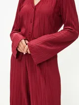 Camisa negra con textura plisada, cuello clásico, escote en V y mangas largas.