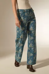 Pantalon de jean de corte recto con estampado floral en tonos claros sobre base azul. Presenta bolsillos funcionales y tiro medio.