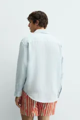 Camisa de corte relajado confeccionada en tejido de lino, con cuello solapa, manga larga con puños abotonados y cierre frontal de botones.
