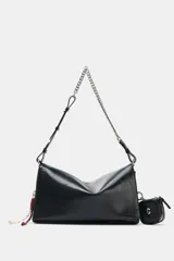 Bolso de hombro tipo baguette en color negro, con acabado brillante y estructura rectangular. Cuenta con una correa combinada de cadena metálica plateada y cuero sintético, y un pequeño monedero extraíble unido a un lateral. Presenta detalles de cordones decorativos en el otro lateral y cierre mediante solapa con imán.