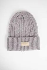 Gorro de lana gris con diseño de trenzas y etiqueta con logo de la marca en el dobladillo.
