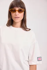Remera de corte oversize y mangas cortas, color blanco, con cuello redondo y detalle de etiqueta pequeña en la manga.