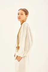 Camisa corta de corte regular, confeccionada en algodón con hilos de lurex. Mangas amplias con elástico interno.