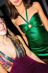 Vestido corto de satén color verde azulado (teal) con escote strapless y detalle de frunce central con argolla. Presenta tirantes finos que se atan al cuello y aberturas laterales en la cintura.