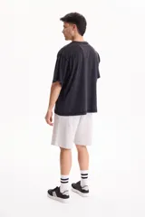 Remera oversize de manga corta en color negro con efecto acid wash. Presenta un pequeño estampado frontal con texto en inglés y un isotipo de flor en la parte superior del pecho.