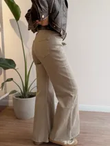 Pantalón de jean estilo wide leg de tiro alto, confeccionado en tela elástica. Presenta un diseño de corte amplio desde la cadera hasta el ruedo, con cierre y botón frontal, y bolsillos laterales y traseros.
